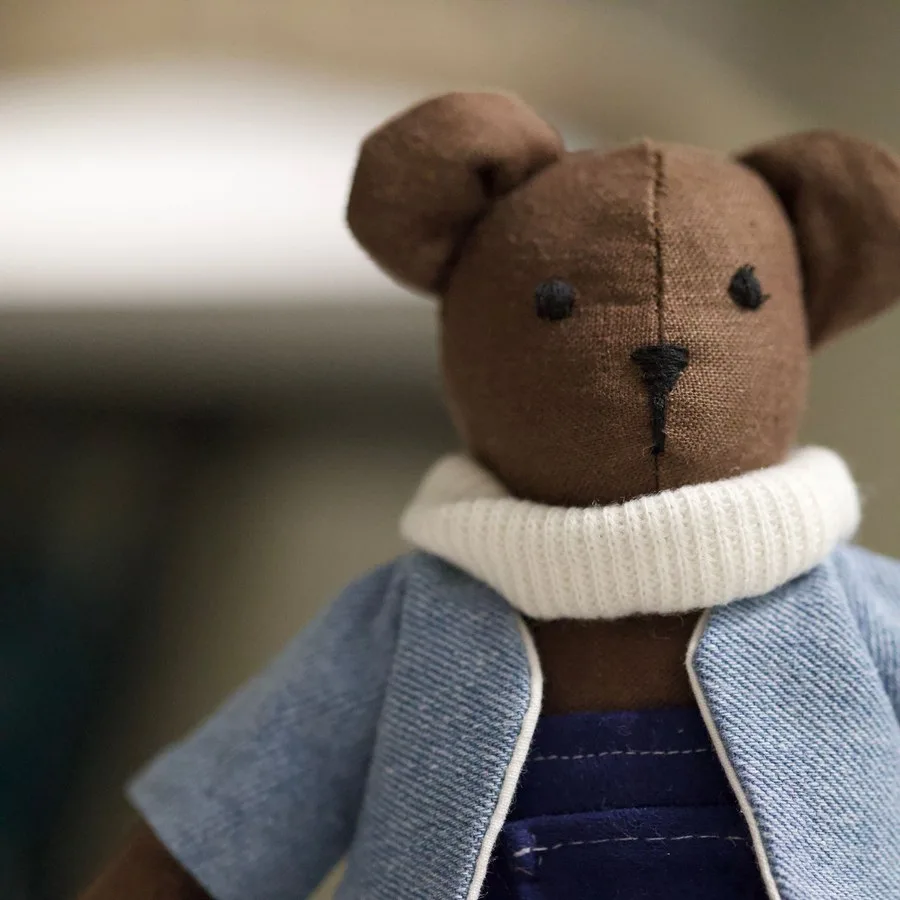 Boneka beruang cokelat memakai jaket biru