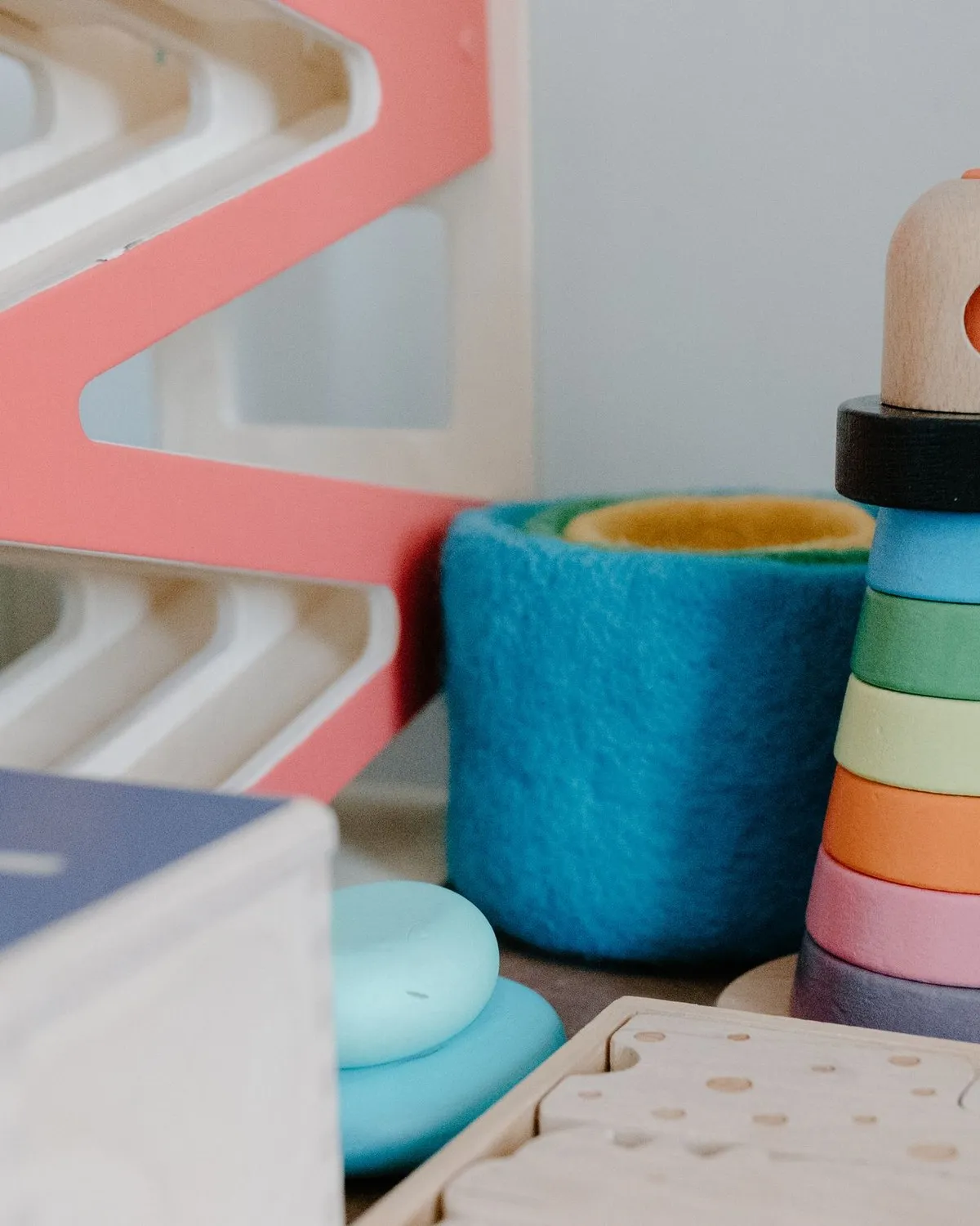 Mainan susun dan mangkuk warna pastel di rak